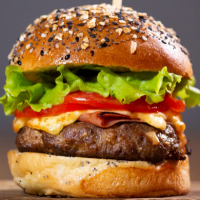 Con nuestro pan casero, carne de ternera menorquina,  lechuga, tomate, queso cheddar, cebolla y lechuga. - HAMBURGUESA SUPREMA